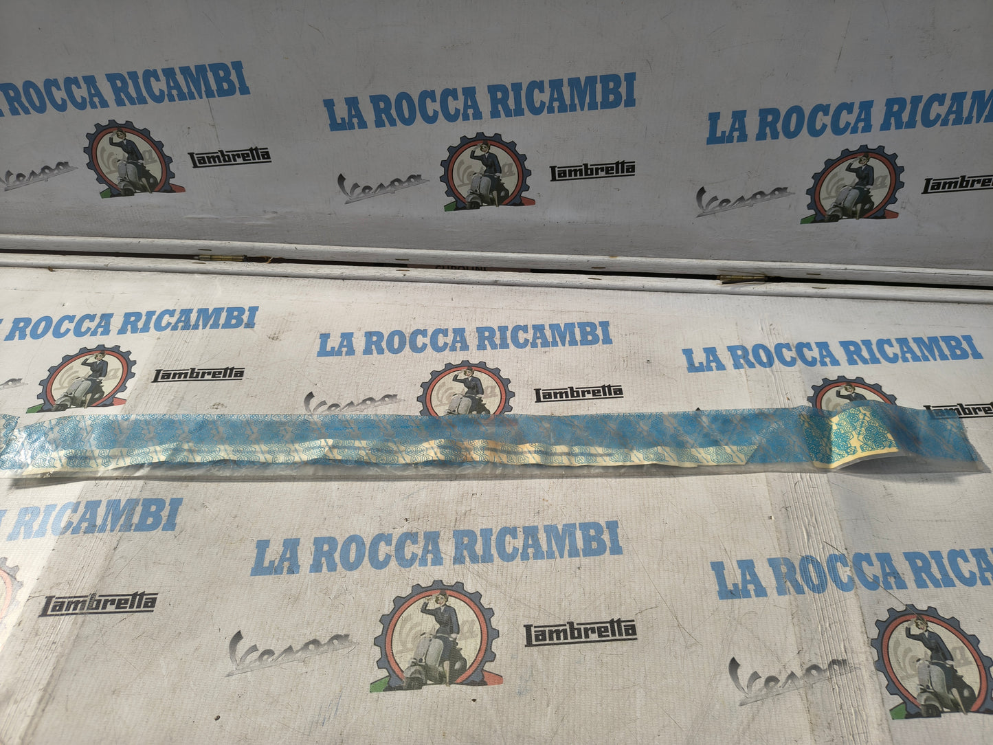 PIAGGIO FREGIO ADESIVO "VESPA" DESTRO SELLA VESPA 50 RUSH COL. BIANCO-BLU 248187